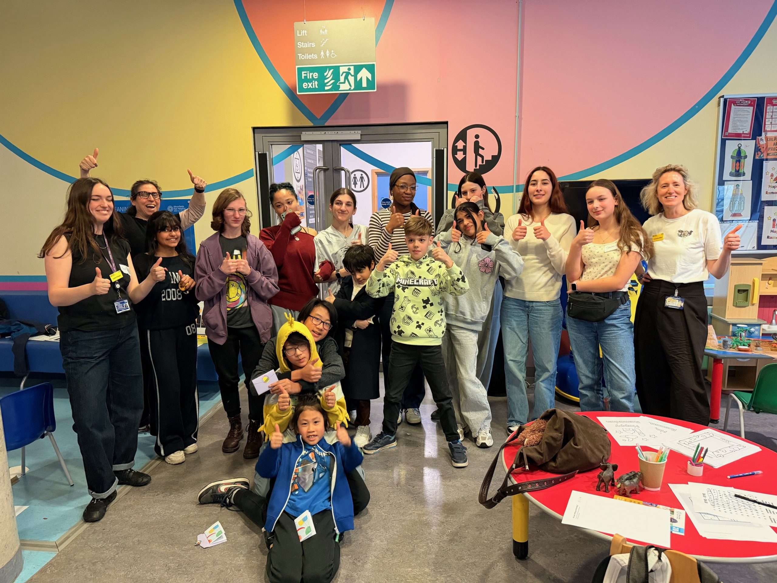 Group photo of young people and facilitators at meeting, doing thumbs up