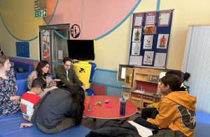 children sat round listening to researchers on sofas